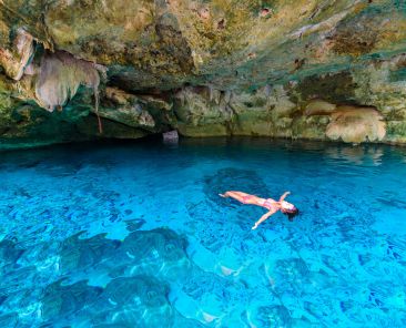 Cenote Dos Ojos in Quintana Roo, Mexico. People swimming and snorkeling in clear blue water. This cenote is located close to Tulum in Yucatan peninsula, Mexico.