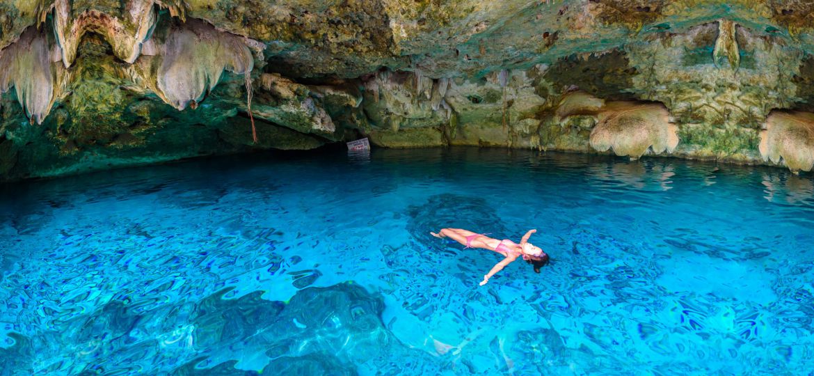 Cenote Dos Ojos in Quintana Roo, Mexico. People swimming and snorkeling in clear blue water. This cenote is located close to Tulum in Yucatan peninsula, Mexico.