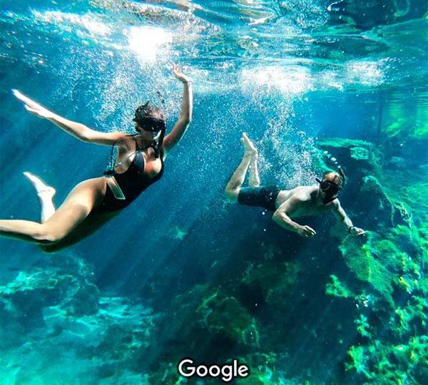young couple of tourist swiming under water in the great cenote