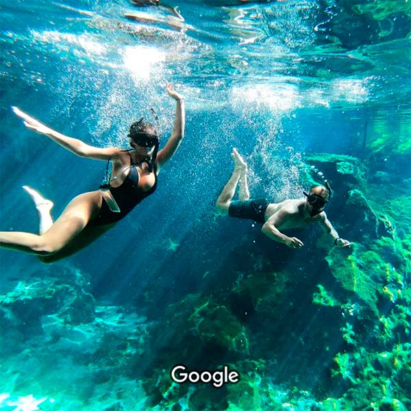 young couple of tourist swiming under water in the great cenote